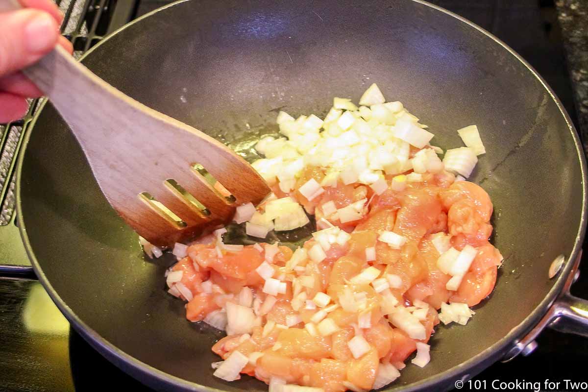 cooking chicken with onion in black pan