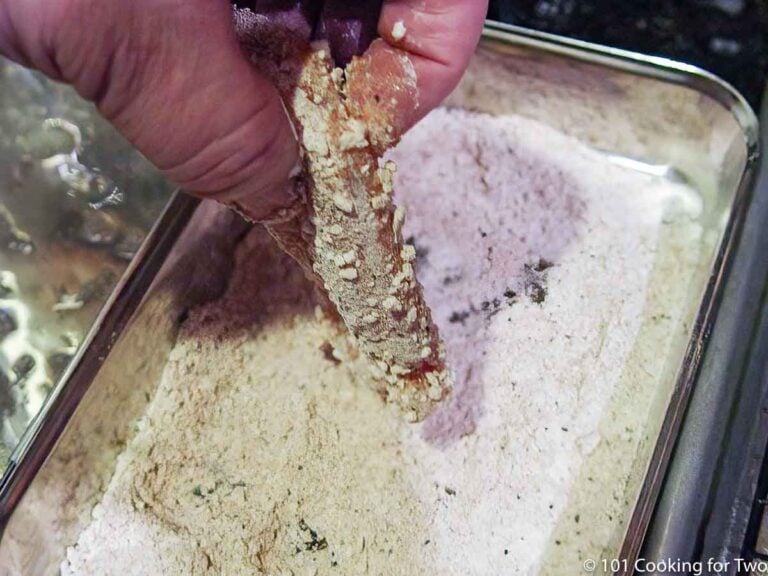 dipping chicken tender in the tray with the coating