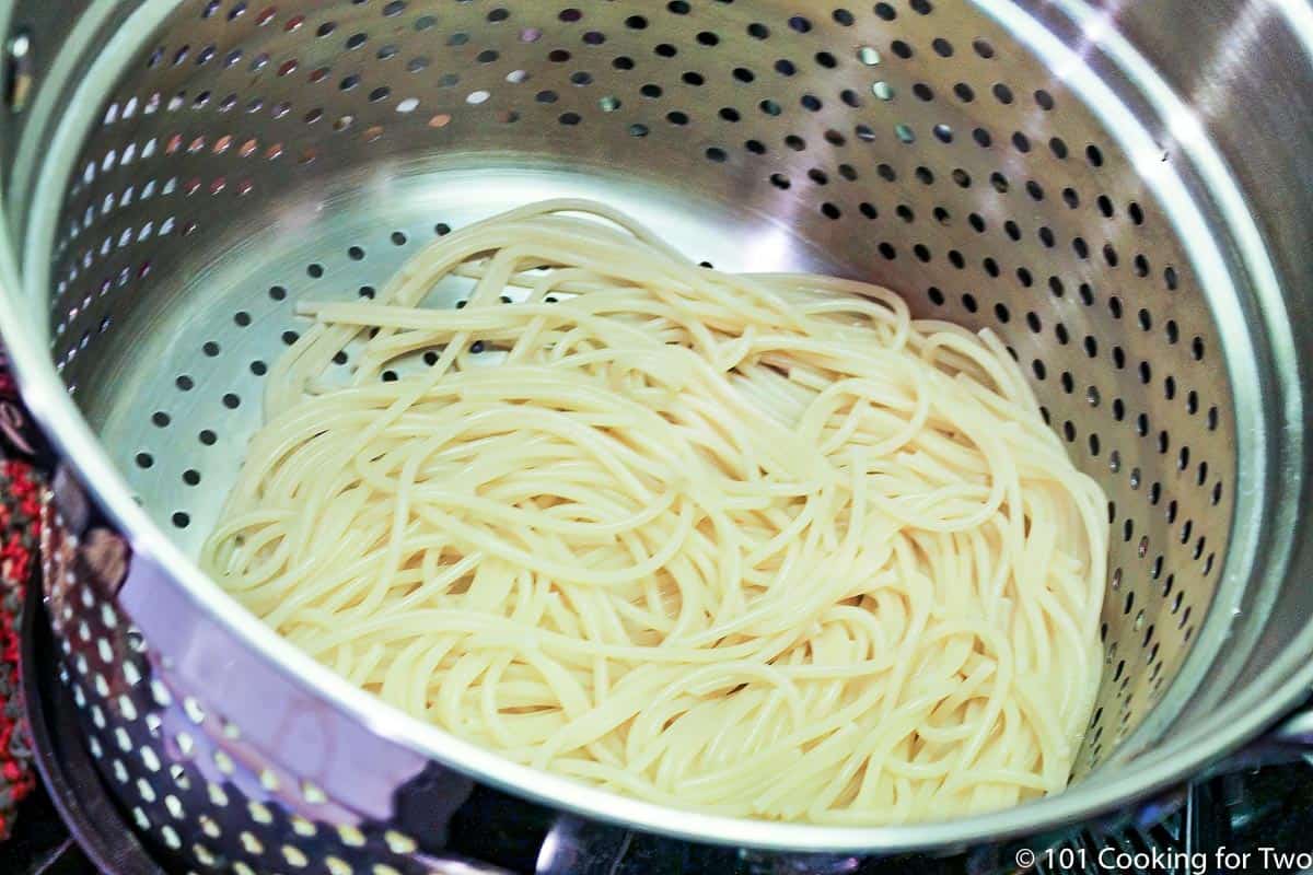 draining cooked pasta.