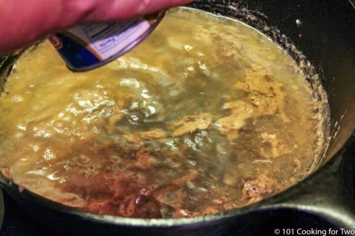 pouring broth into pan with roux