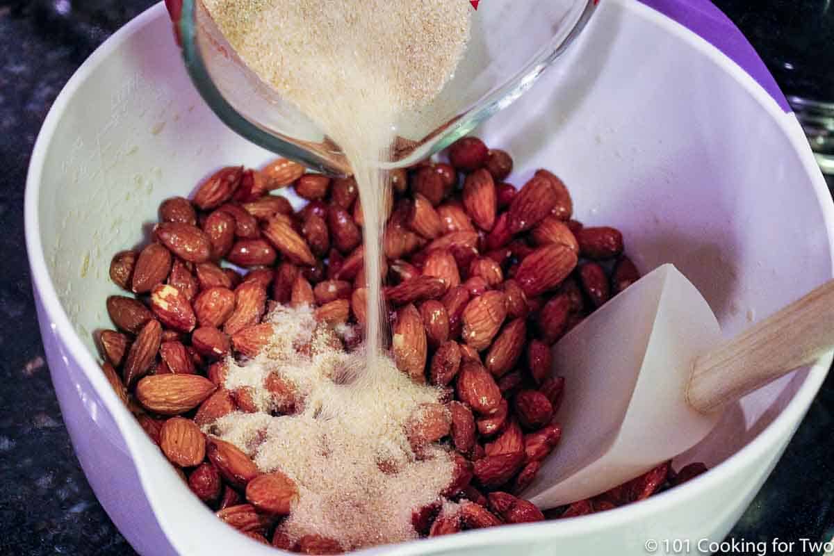 pouring cinnamon sugar over nuts.