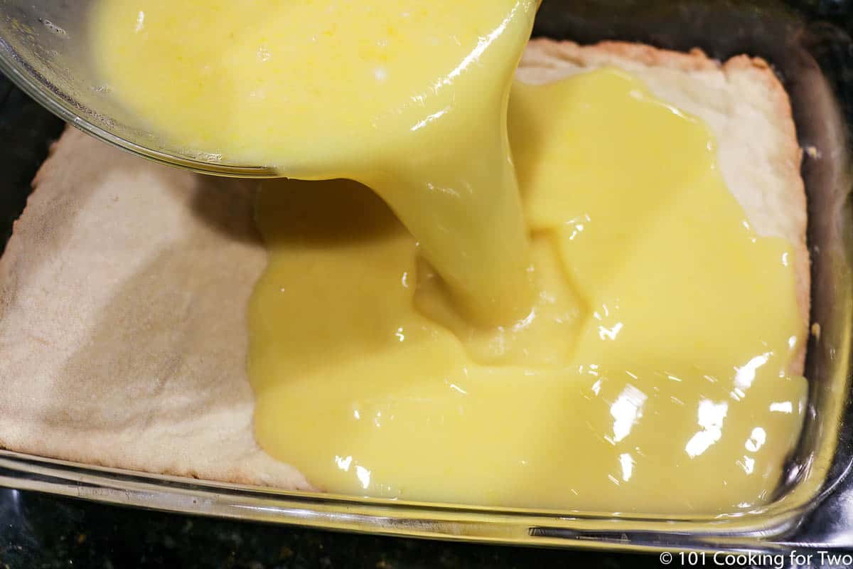 pouring lemon filling over shortbread crust
