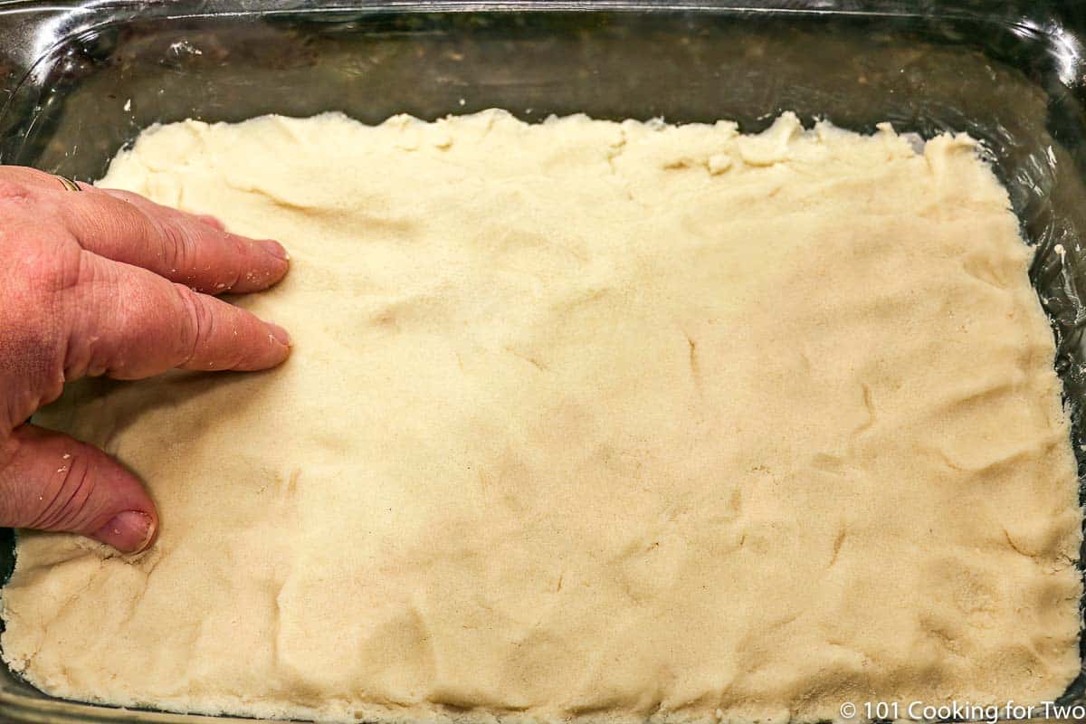 pressing shortbread dough into pan.