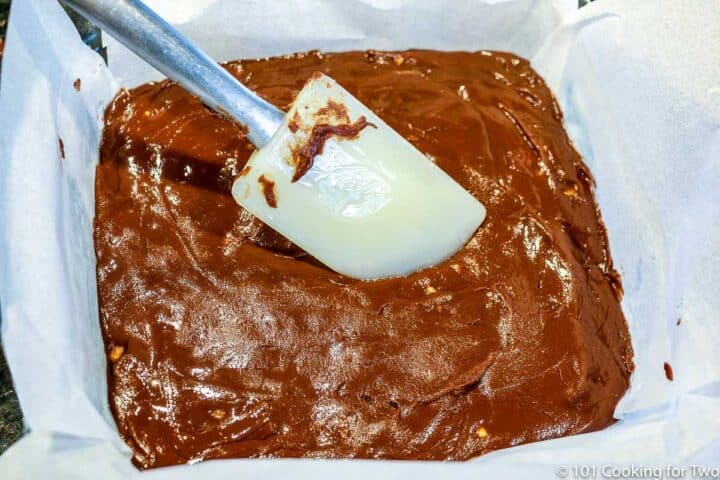 smoothing fudge into pan with parchment paper