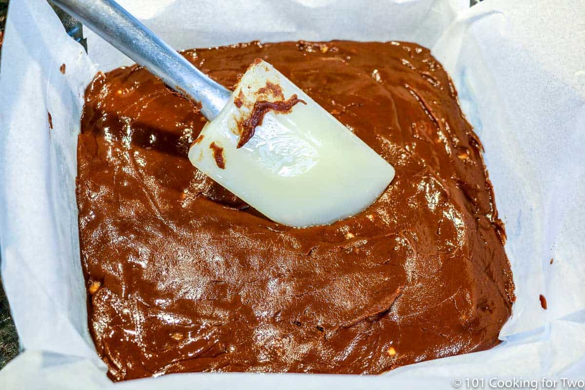 smoothing fudge into pan with parchment paper.