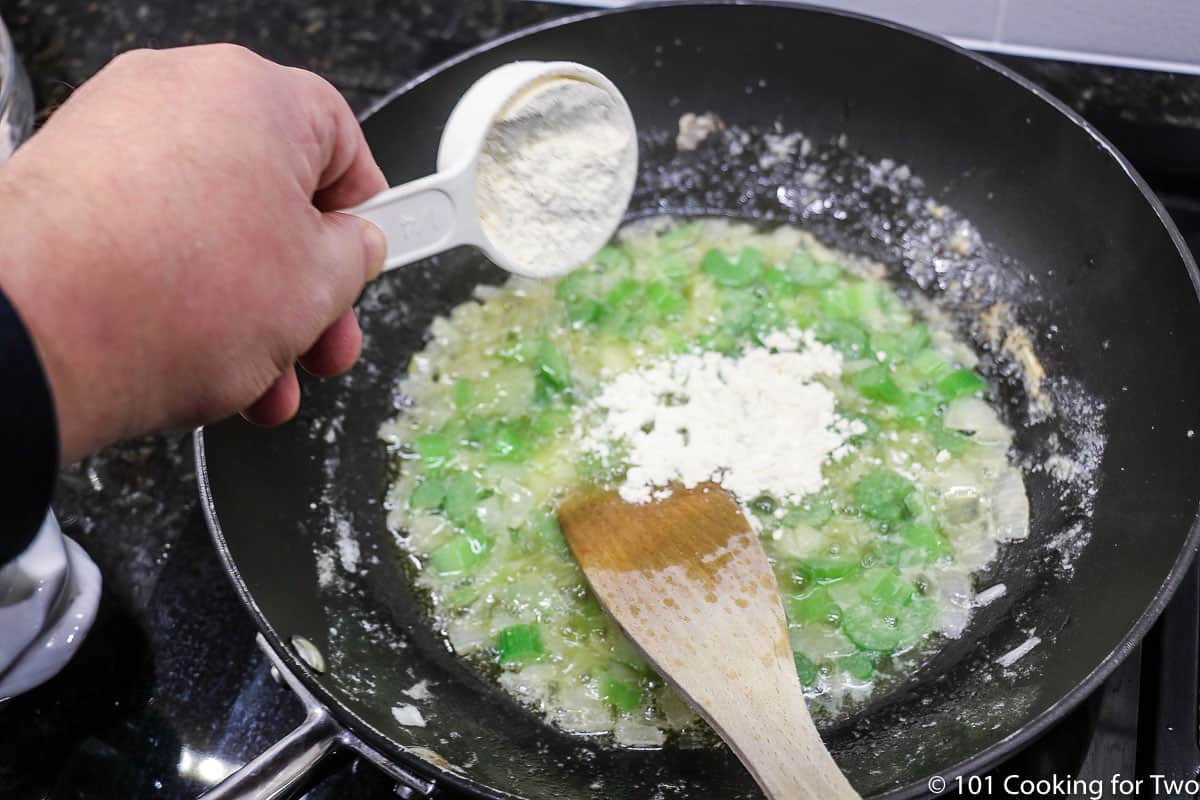 sprinking flour into a pan with celery and butter