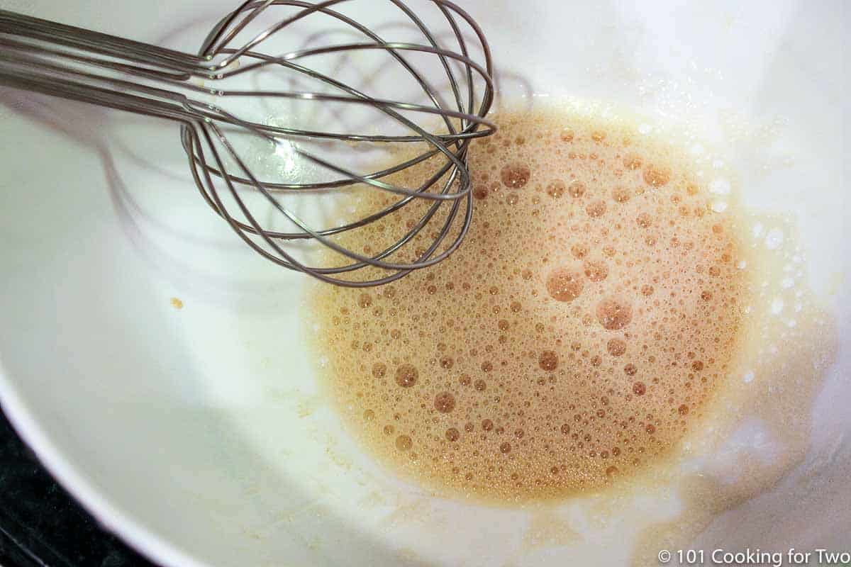 whisking liquid ingredients in a white bowl