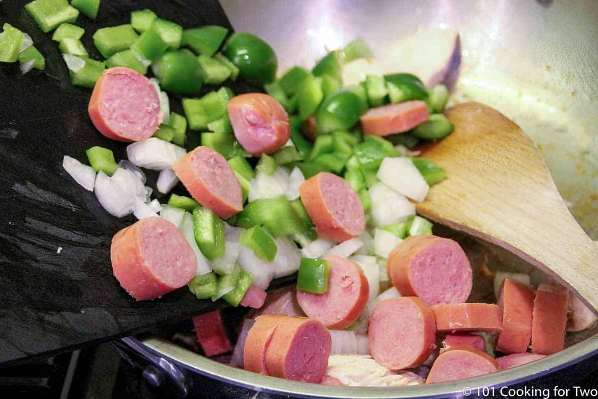 adding sausage with veggies to the pan
