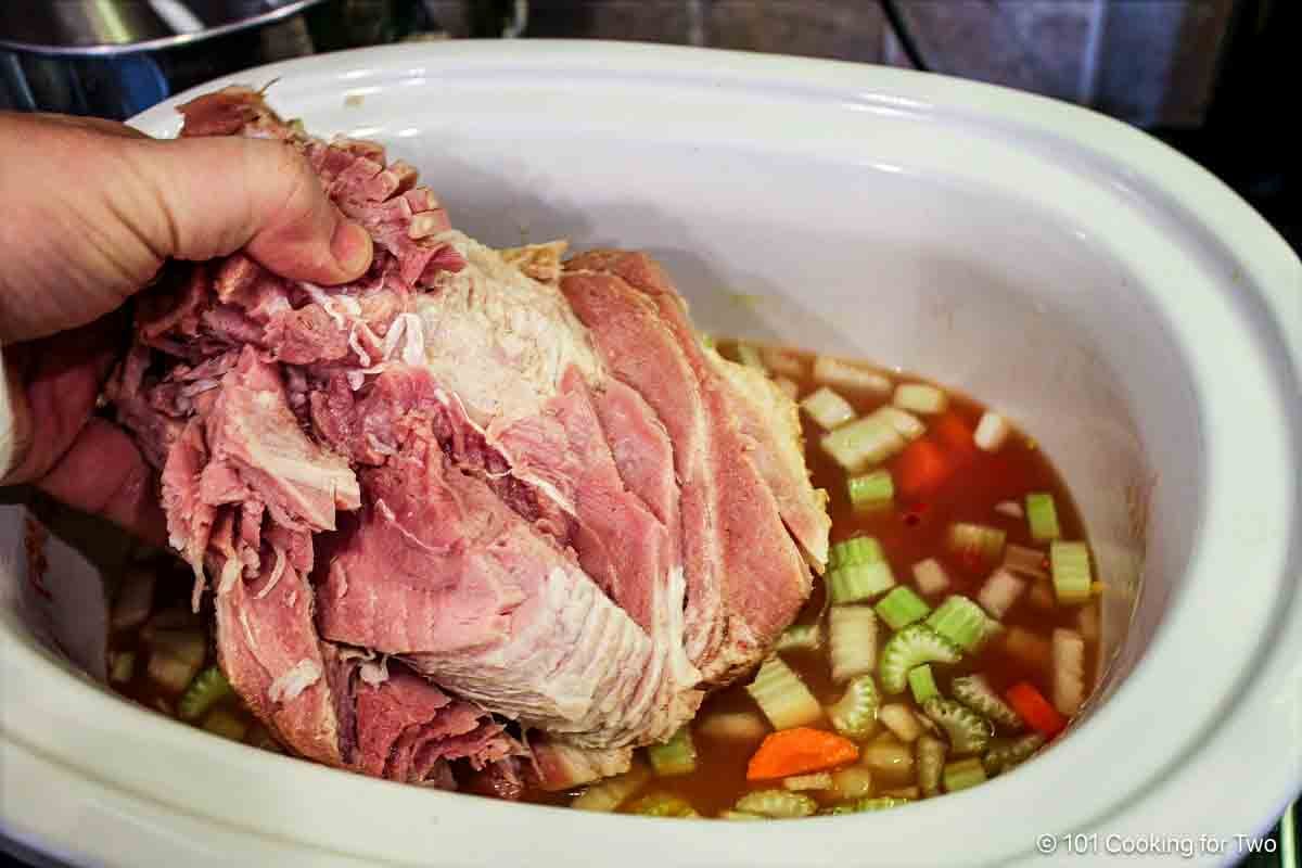 Adding the ham bone to the soup.