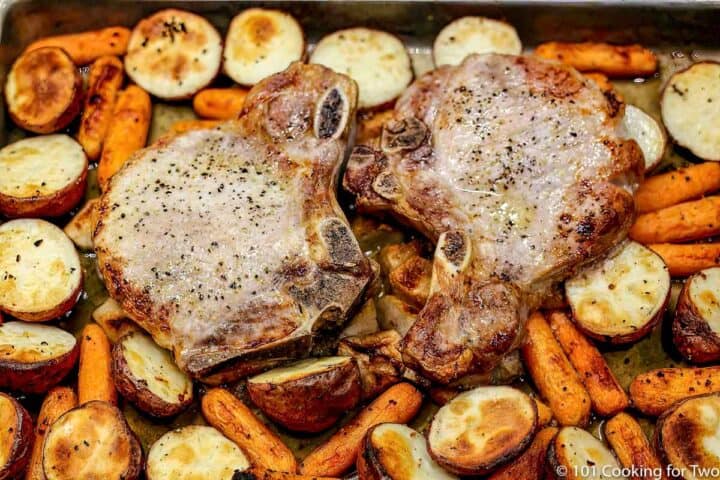 cooked pork chops on top of apples and vegetables cooked