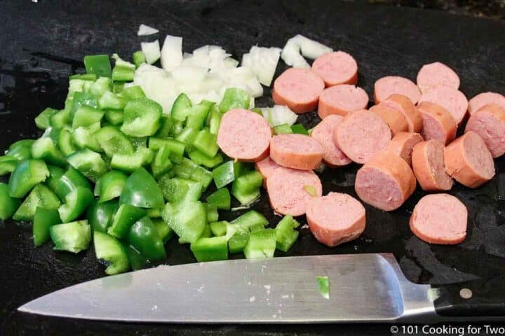 cut up sausage with pepper and onion on a white board