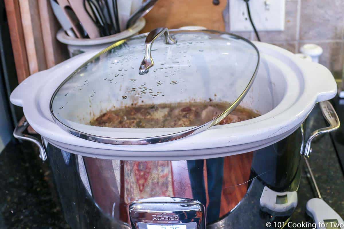 large crock pot with lid set with some opening.