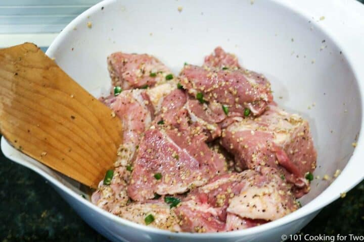 mixing other seasoning into bowl with raw carnitas