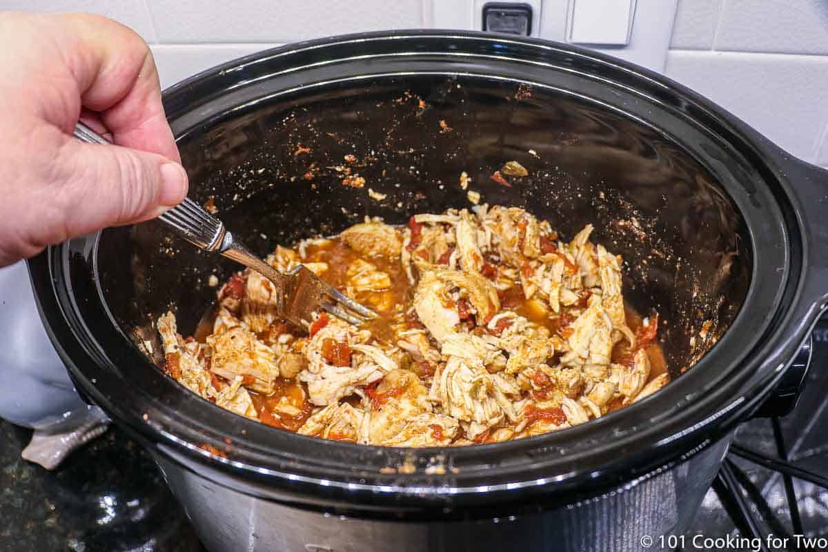 mixing the shredded chicken back into the crock pot