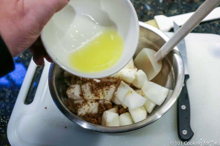 pouring butter into bowl with apple and spices