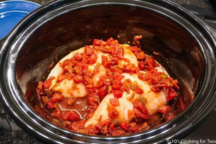 raw chicken in a crock pot covered with sauce