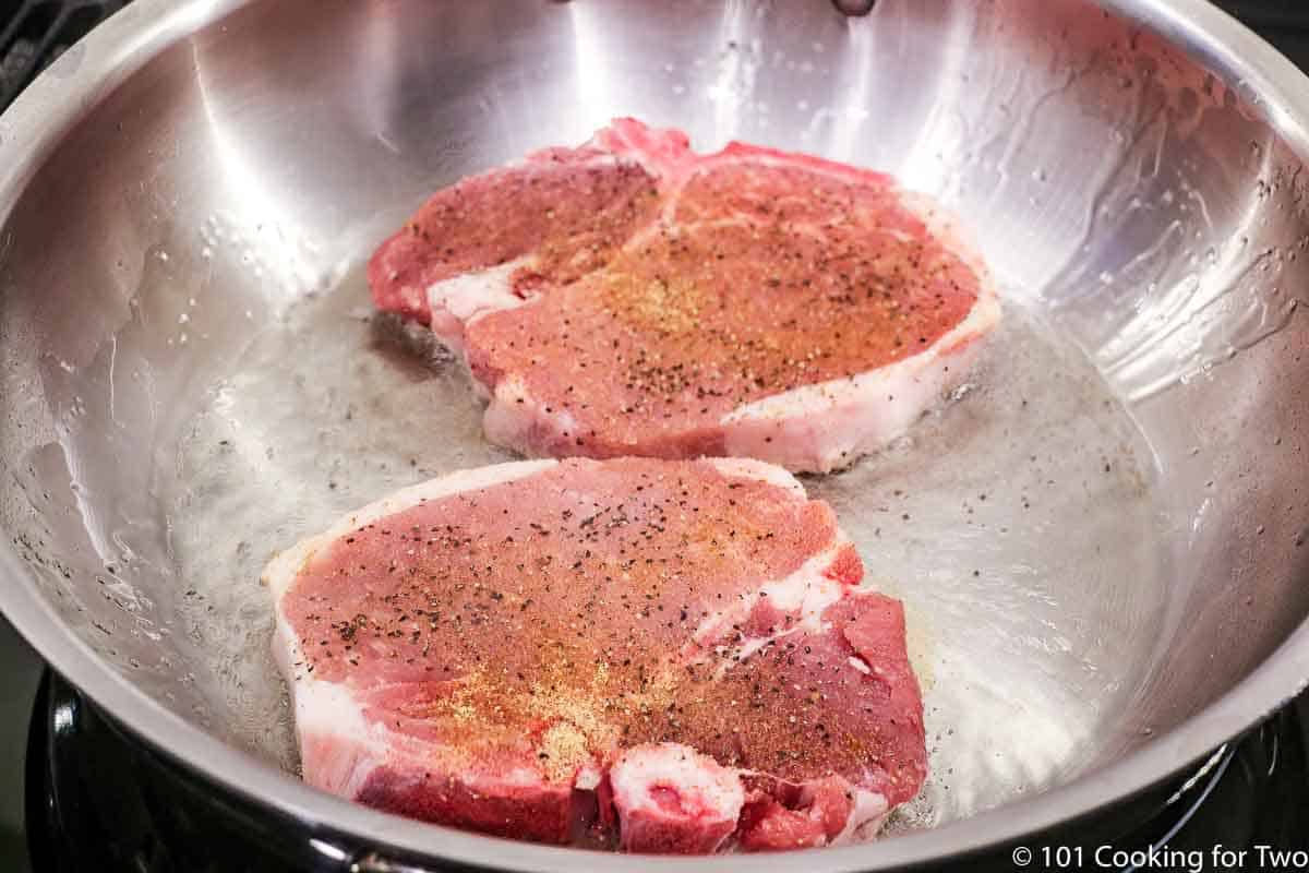 raw pork chops in a pan with hot oil.
