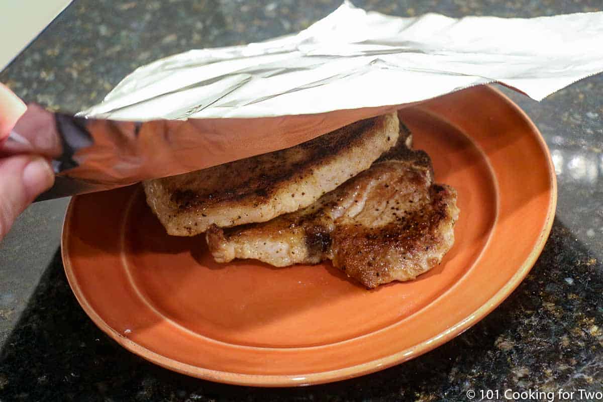 tenting cooked pork chops with foil.