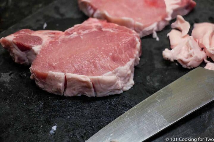 trimming pork chops on a black board