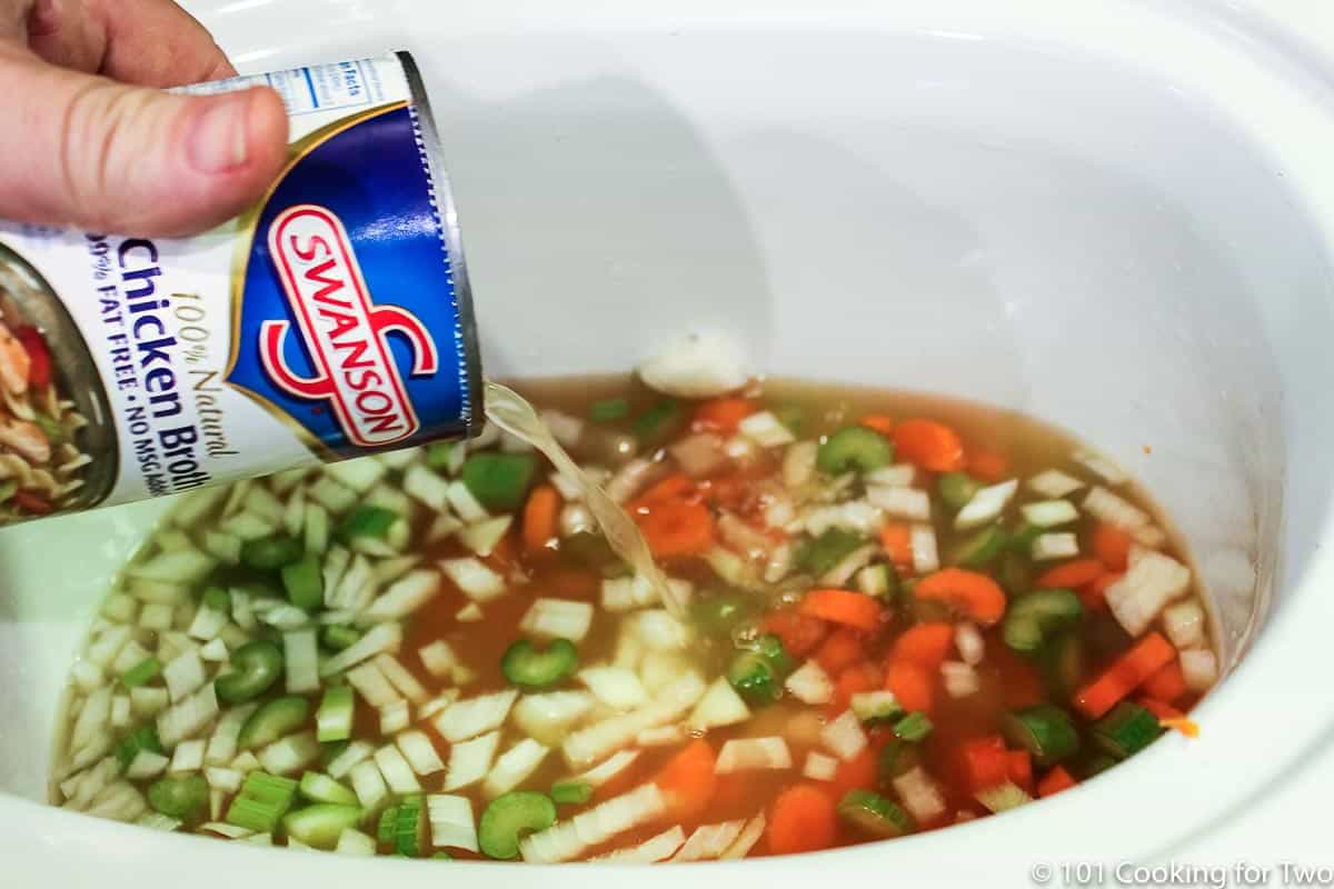adding chicken broth to vegetables in crock pot.