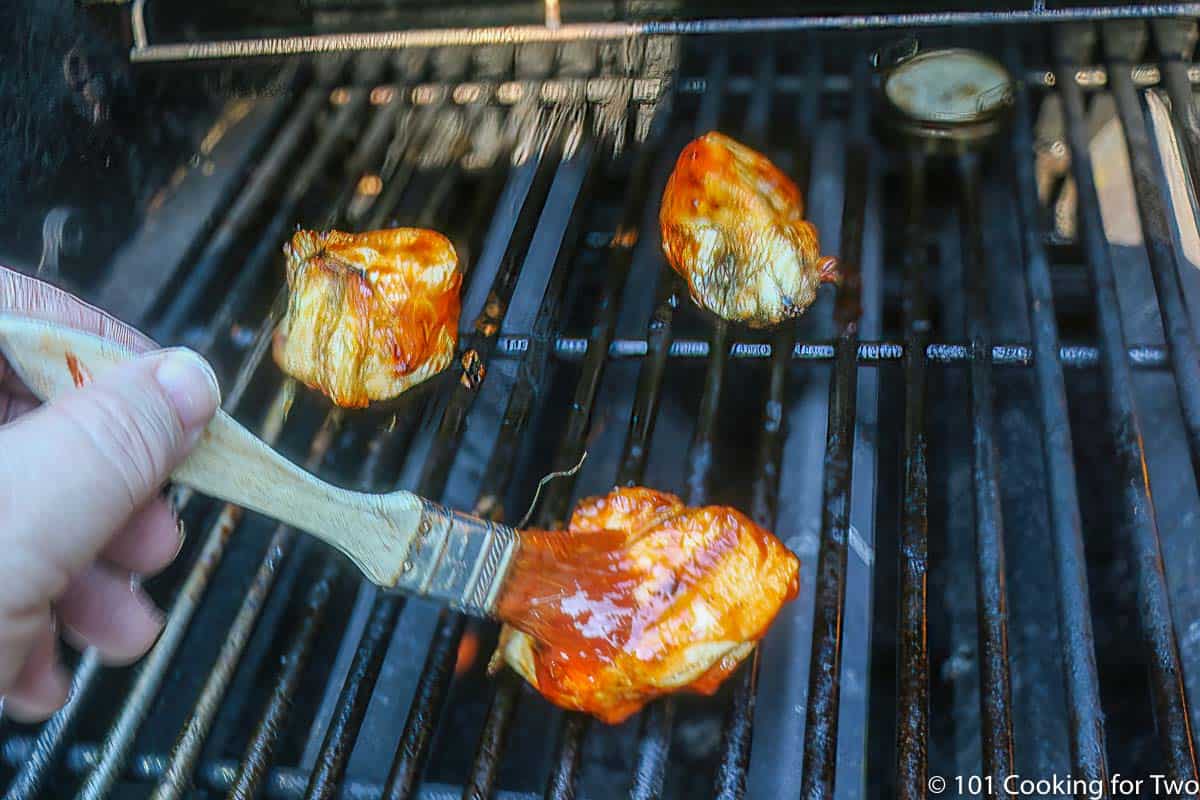 brushing BBQ sauce on split chicken breast