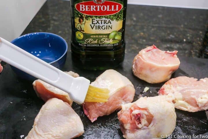 brushing cut up chicken with olive oil