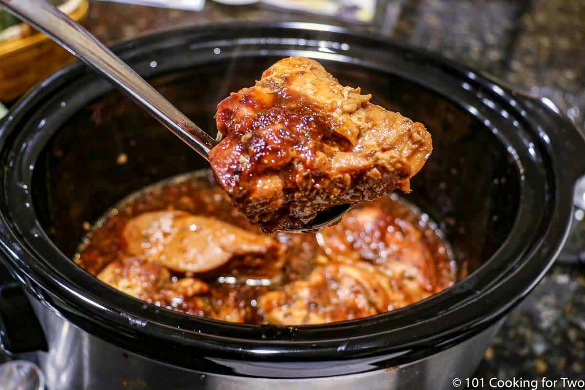 Cooked chicken with sauce on a ladle.