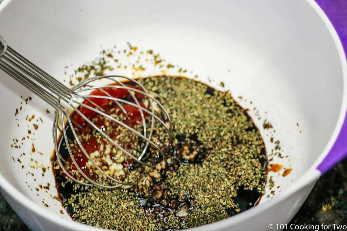 Whisking sauce ingredients in a white bowl.