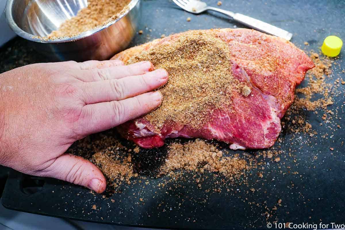 applying a dry rub to pork butt.