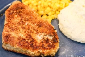 breaded-pork-chop-on-a-blue-plate-with-corn-and-potatoes