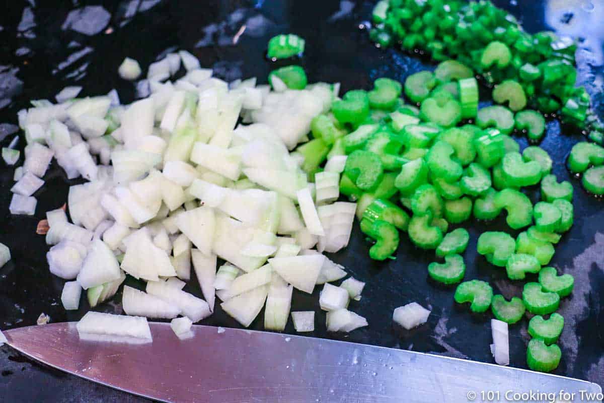 chopped onion with celery and jalapeno on a black board
