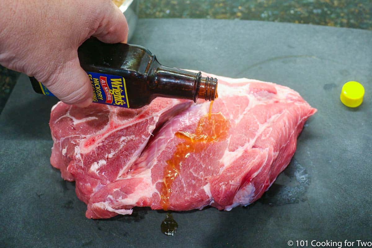 coating a pork butt with liquid smoke.