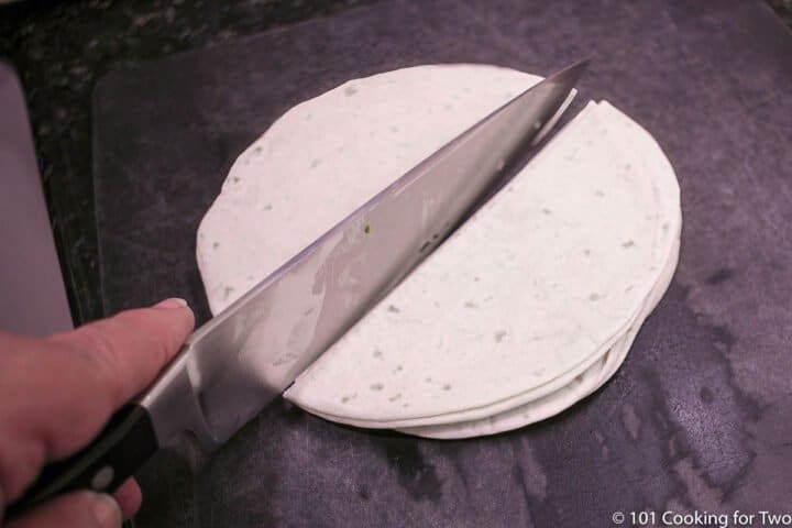cutting a stack of flour tortillas on black board