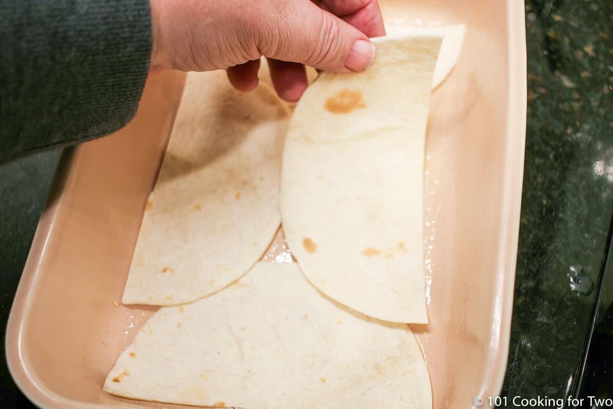 layering half tortillas into casserole dish