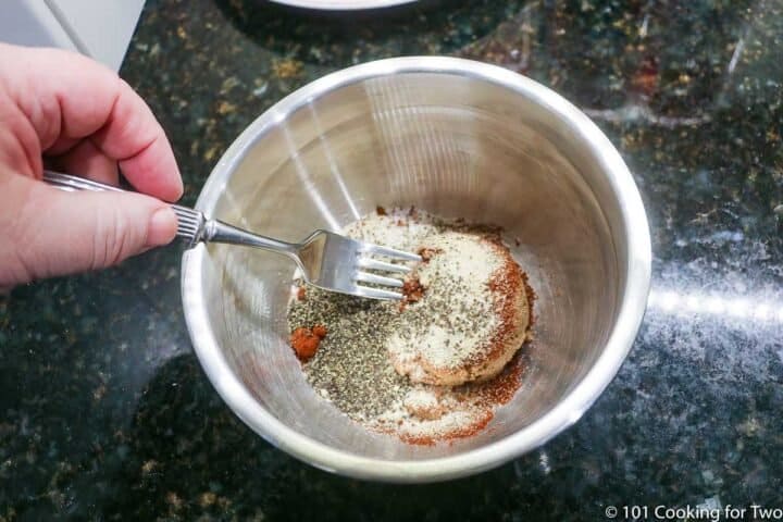 mixing rub ingredients in metal bowl.