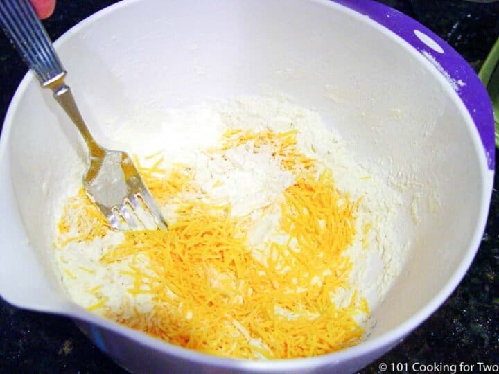 mixing shredded cheese into dry ingredients