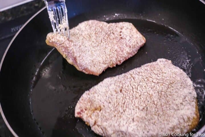 placing pork chop in the frying pan with oil