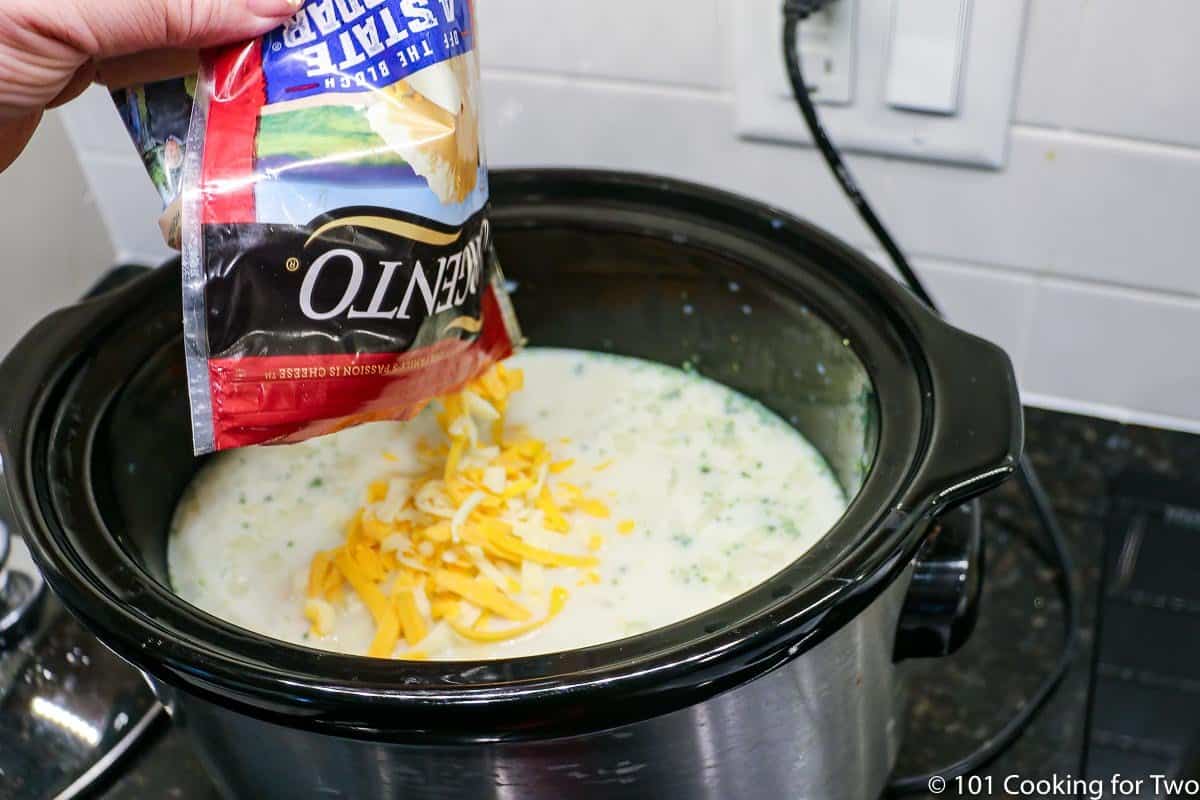 pouring shredded cheese into crock pot.