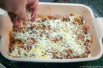 sprinkling shredded cheese over layer of meat