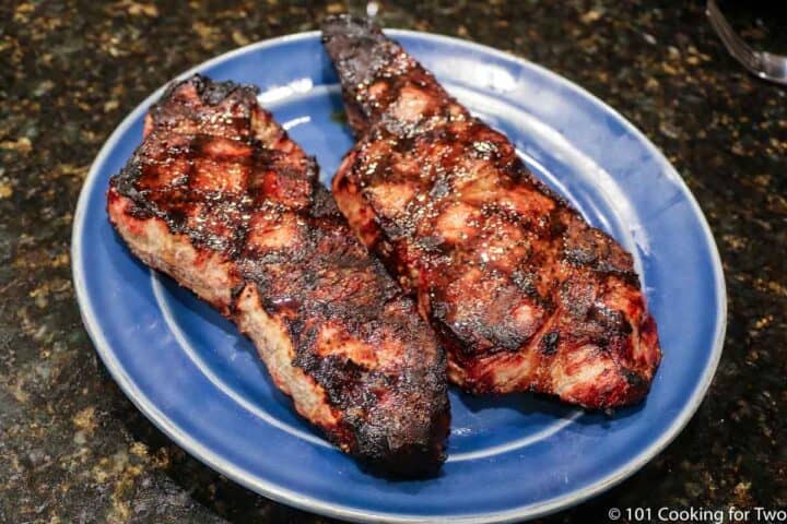 two grilled strip steaks on a blue plate