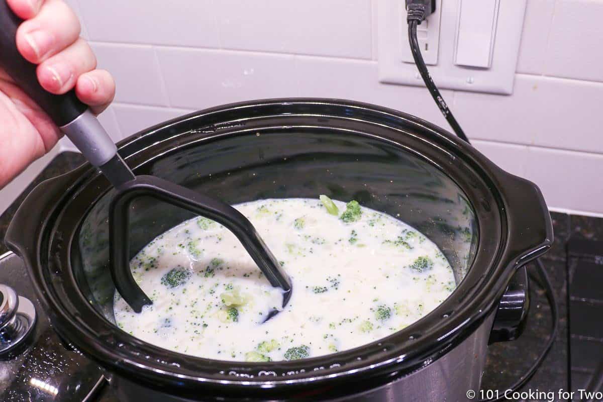 using a potato masher to break up soup in crock pot.