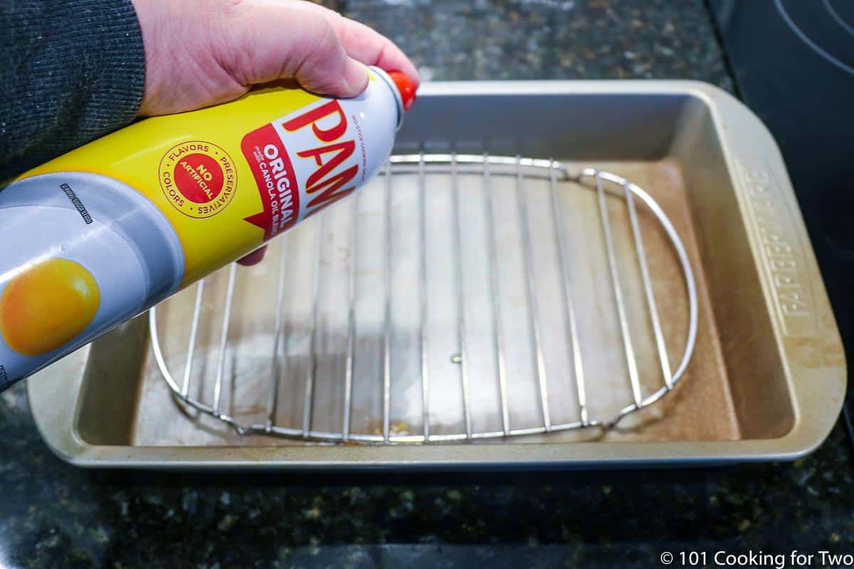 spraying a rack in a cake pan.