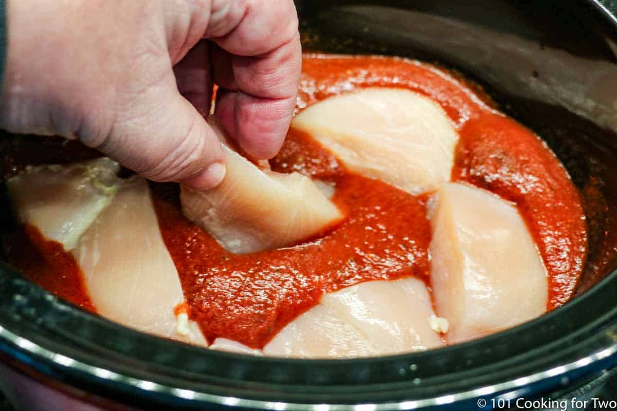 adding raw chicken to sauce in crock pot