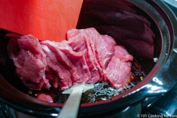 adding sliced beef to the crock pot