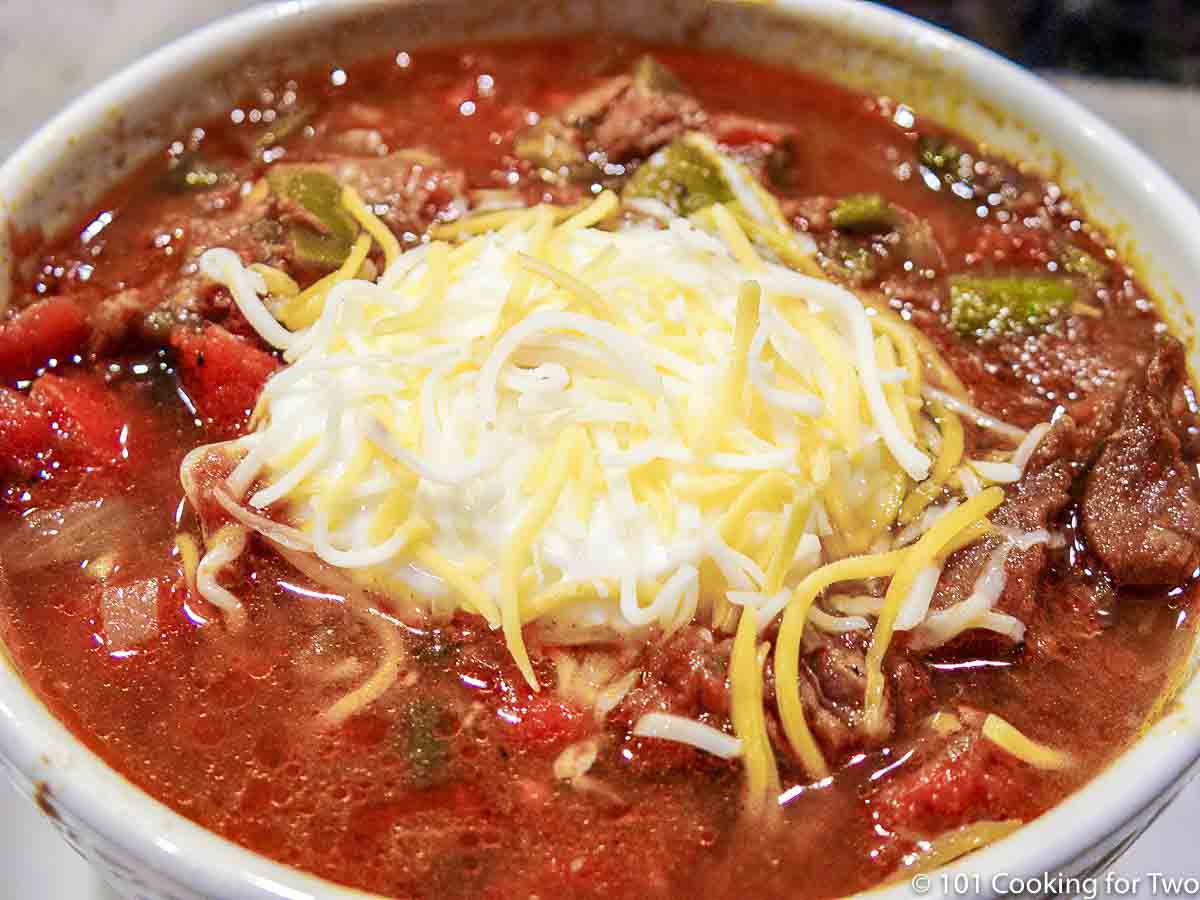 bowl of chili topped with sour cream and cheese.