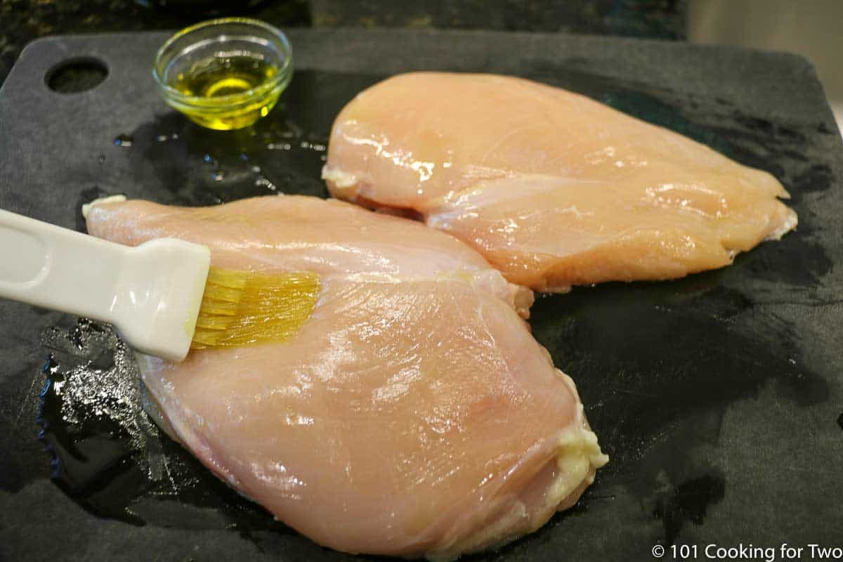 brushing olive oil on chicken.
