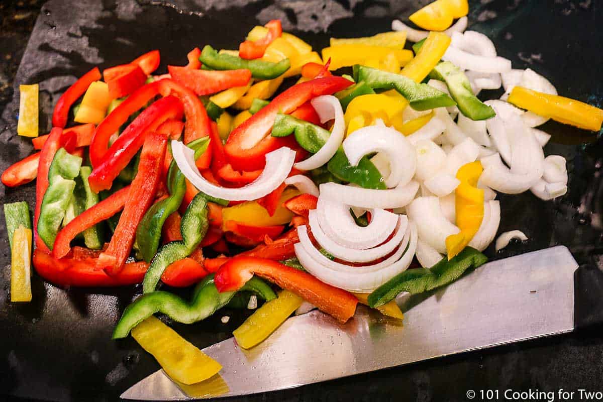 chopped peppers and onion on a black board.