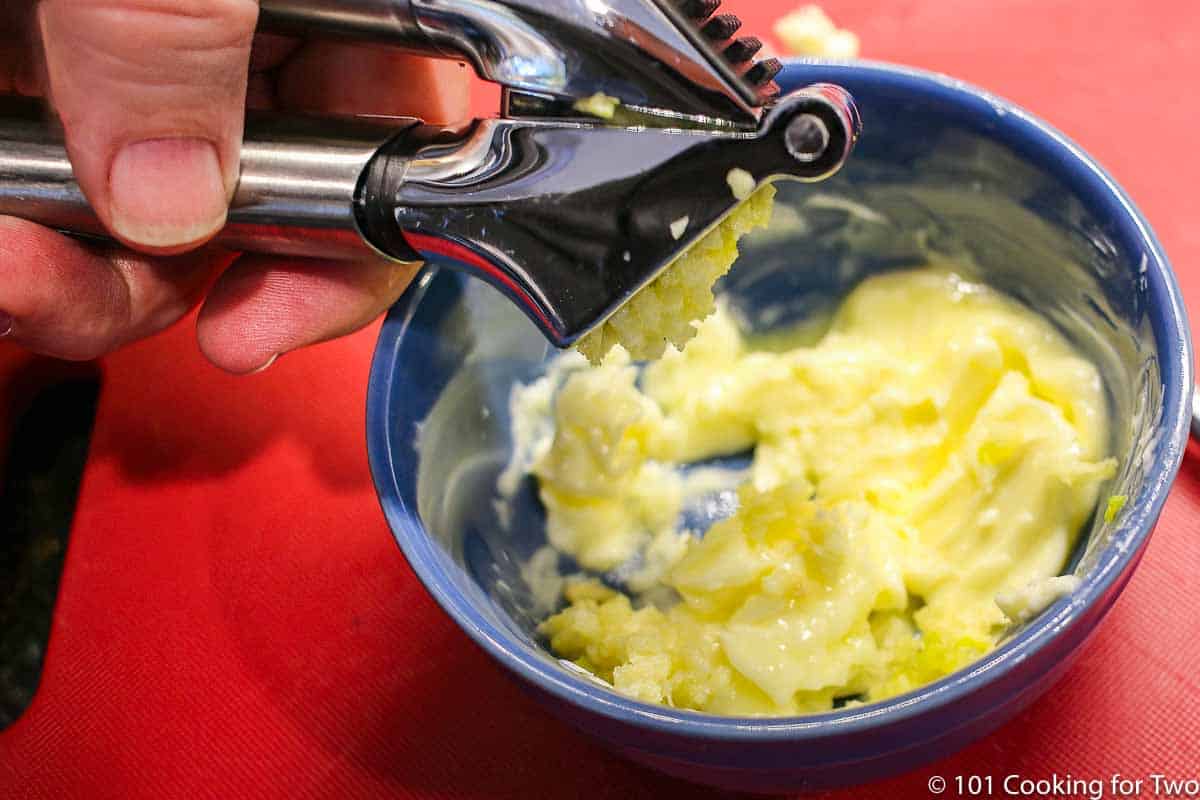 crushing garlic into softened butter in a small bowl.