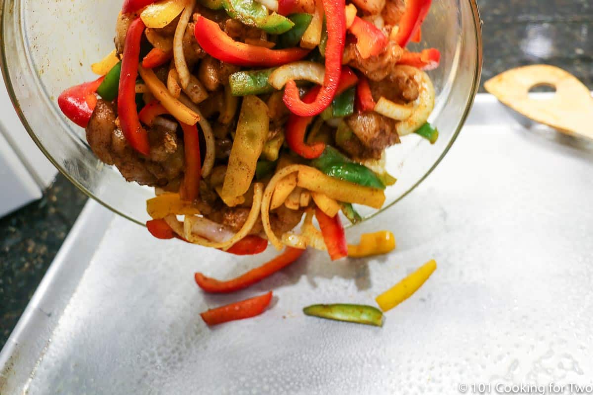 pouring vegetables and chicken onto sheet pan.