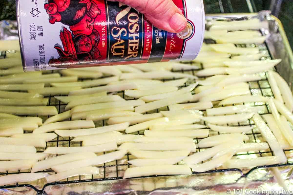 raw French fries on rack with salt